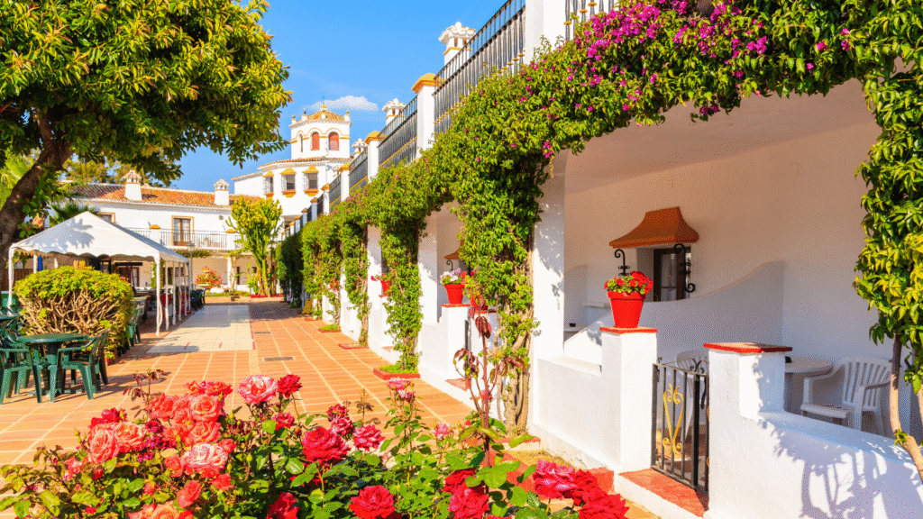 Andalusian-style courtyard in Marbella, Costa del Sol — whitewashed walls, terracotta tiles, and colorful Mediterranean -Quintessentia Property Advisors