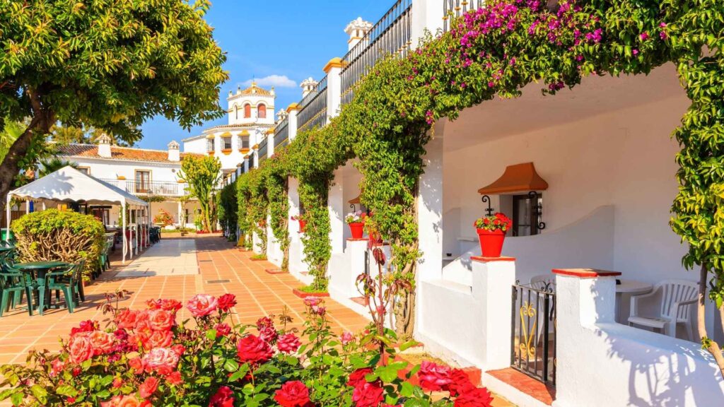 Charming traditional Andalusian street in Marbella, Spain, with whitewashed houses, flowers, and Mediterranean-style architecture, showcasing the character of Marbella’s top property areas.