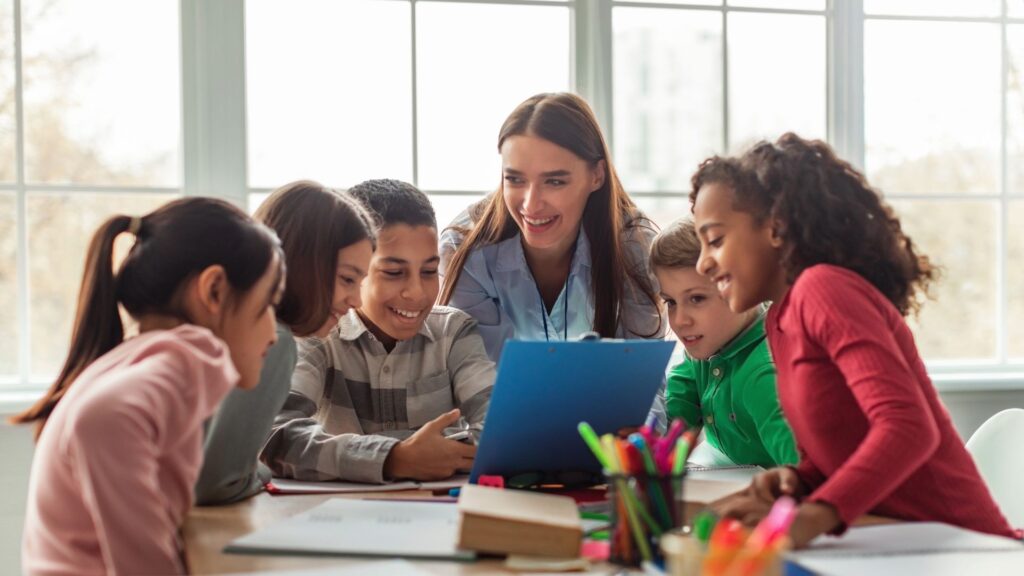 Teacher guiding international students during a collaborative classroom activity at a modern school in Marbella.