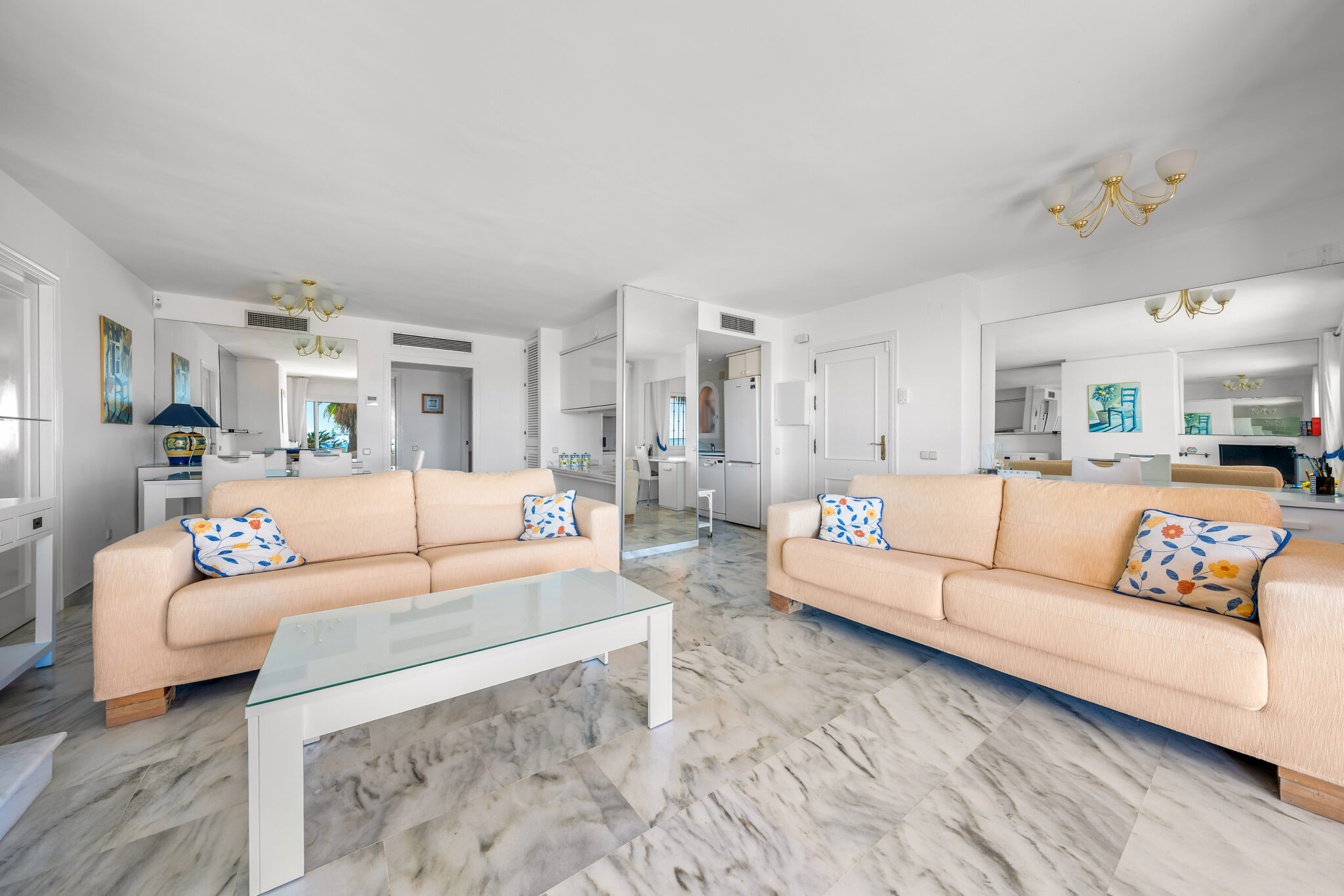 Open-plan living area with large windows facing the garden in Estepona apartment