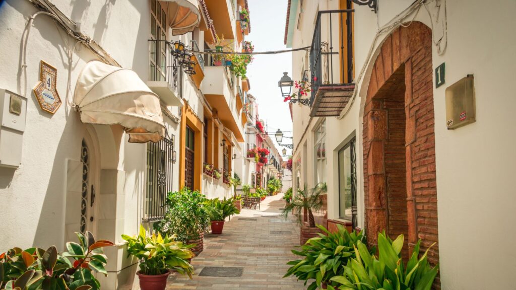 Picturesque narrow street in Marbella with whitewashed buildings, potted plants, and traditional Spanish balconies