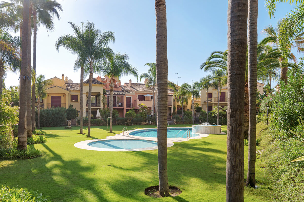Tropical gardens and communal swimming pool in Mediterranean-style townhouse complex in Marbella