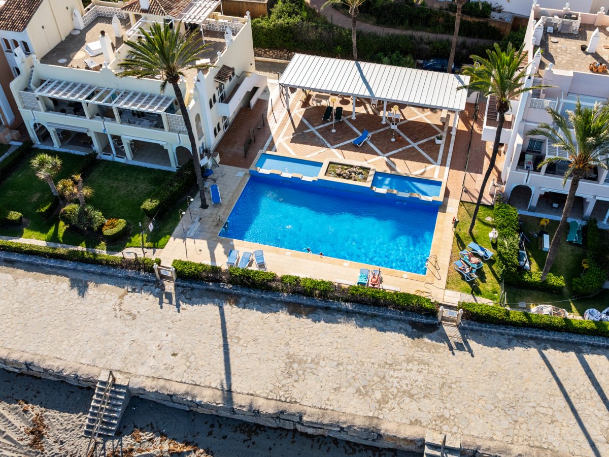 Aerial view of Playa del Moral beachfront apartments with communal pool and gardens overlooking the Mediterranean Sea