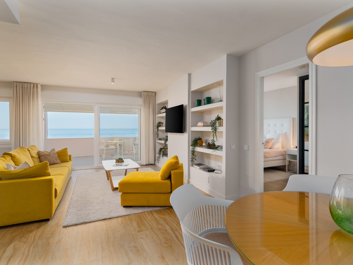 Modern beachfront living room with sea views, yellow sofas, and dining area in Playa del Moral apartment