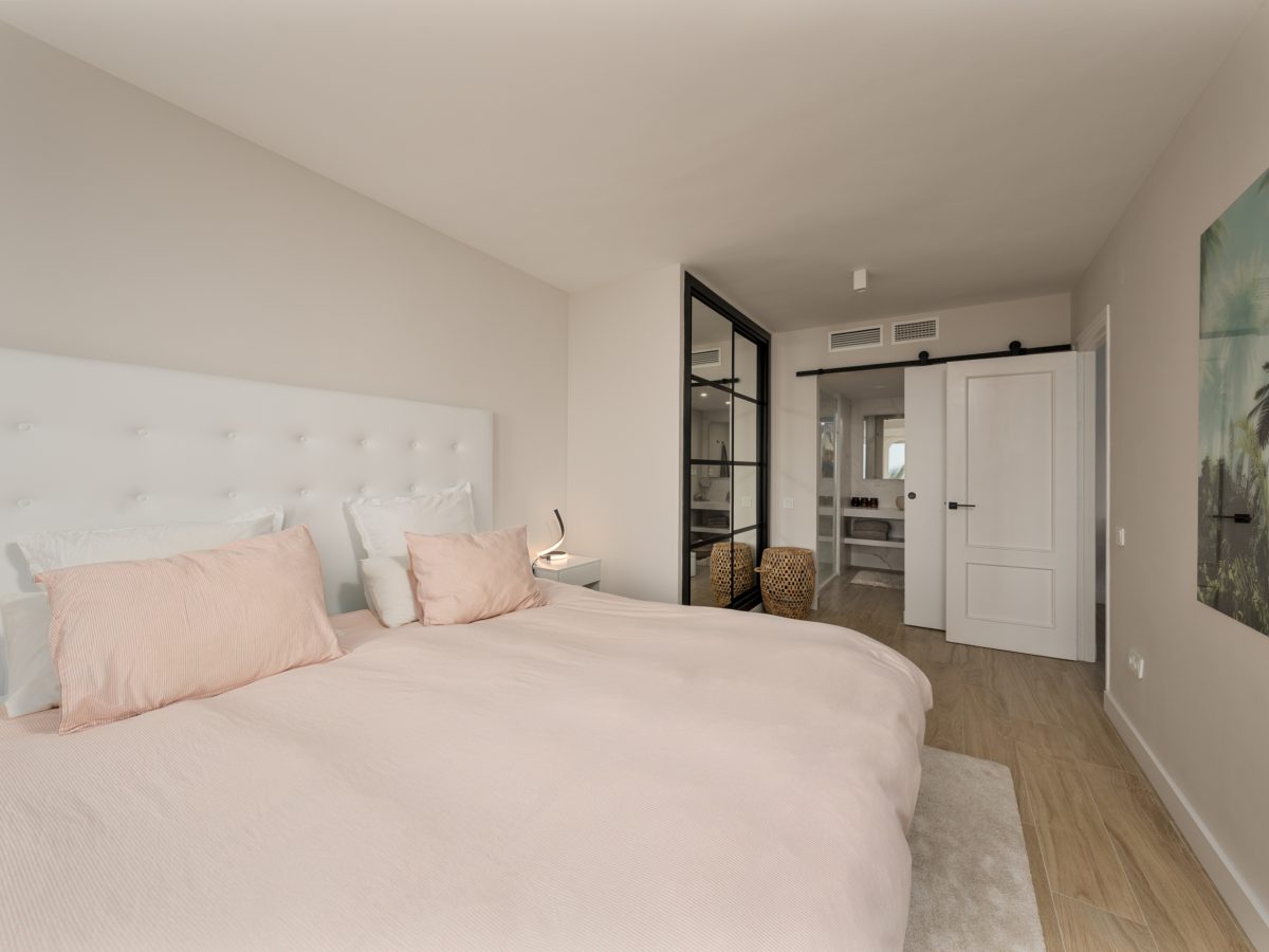 Bright bedroom with soft pink bedding and modern en-suite design in Playa del Moral apartment