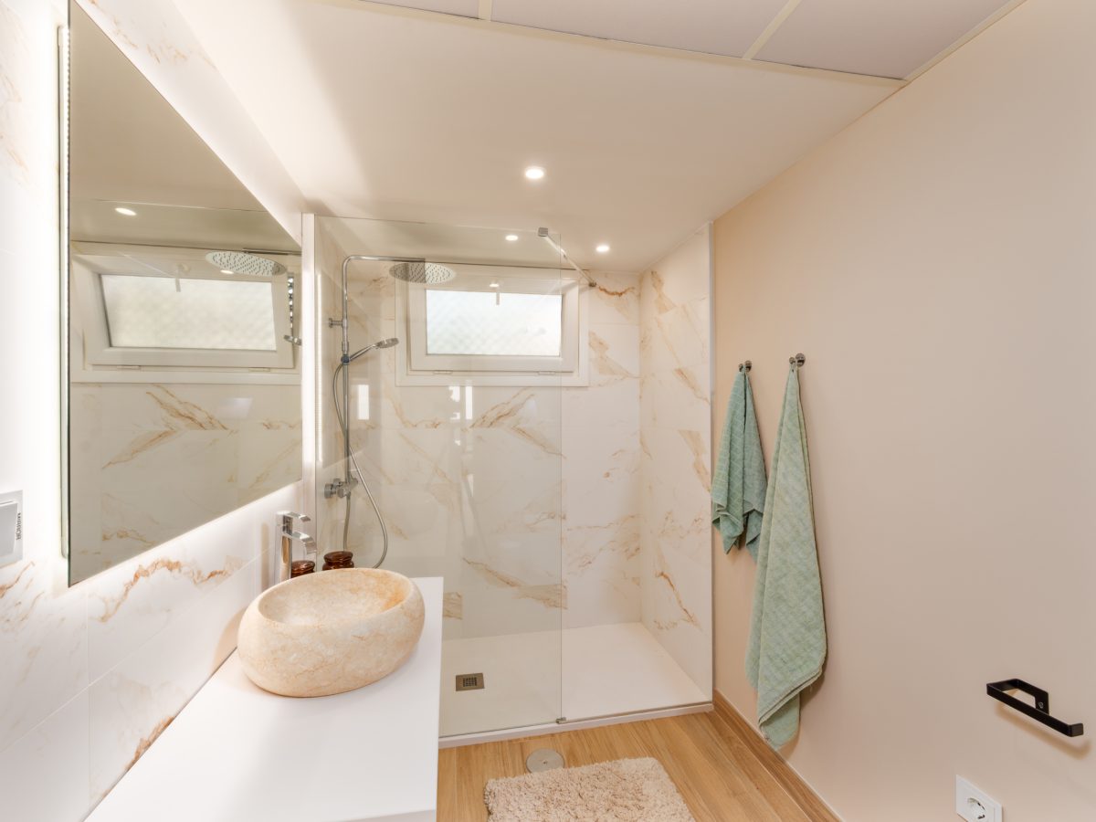 Modern bathroom with marble shower and stone sink in Playa del Moral beachfront apartment.