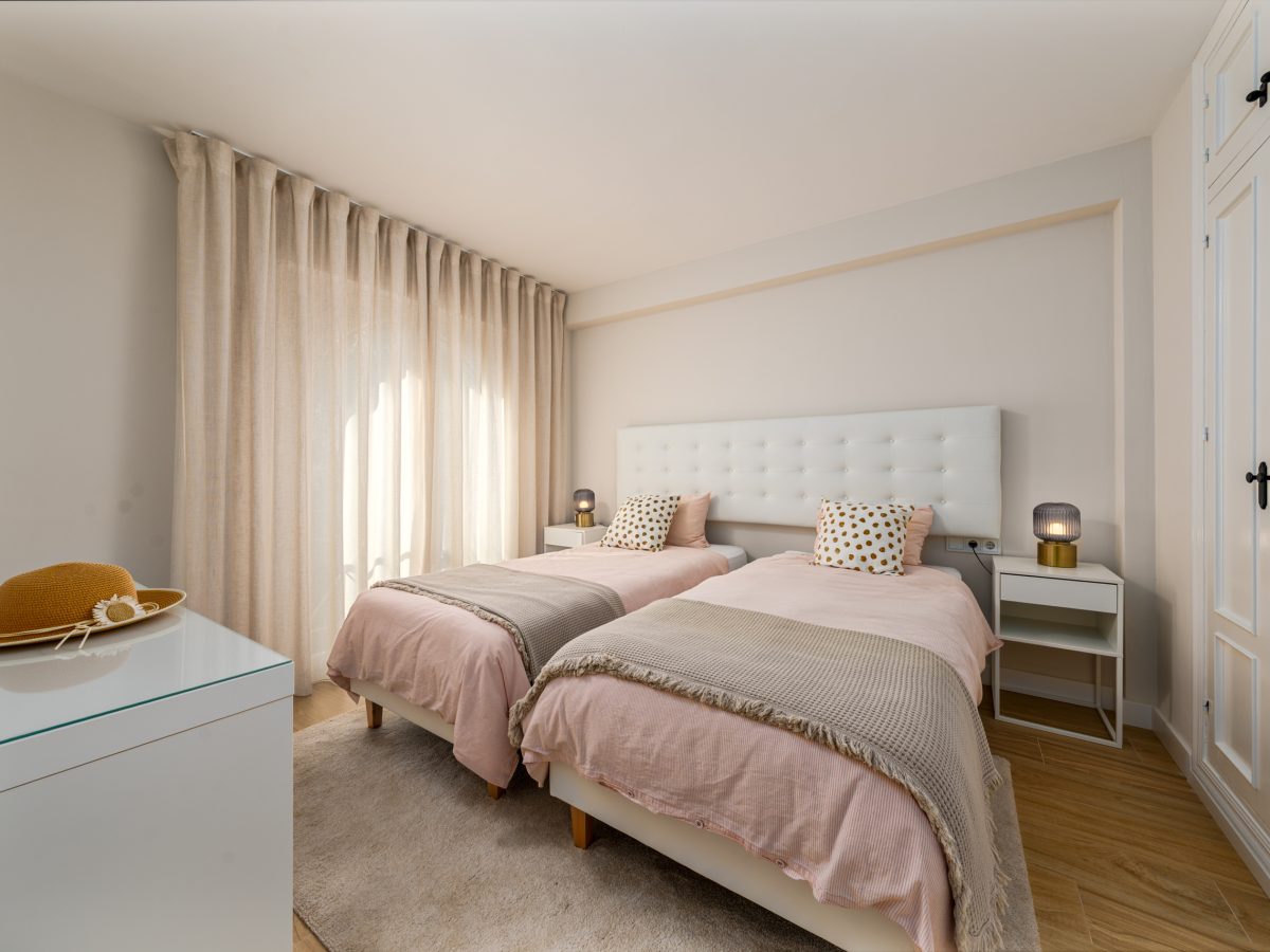 Bright twin bedroom with large windows and balcony at Playa del Moral apartment.