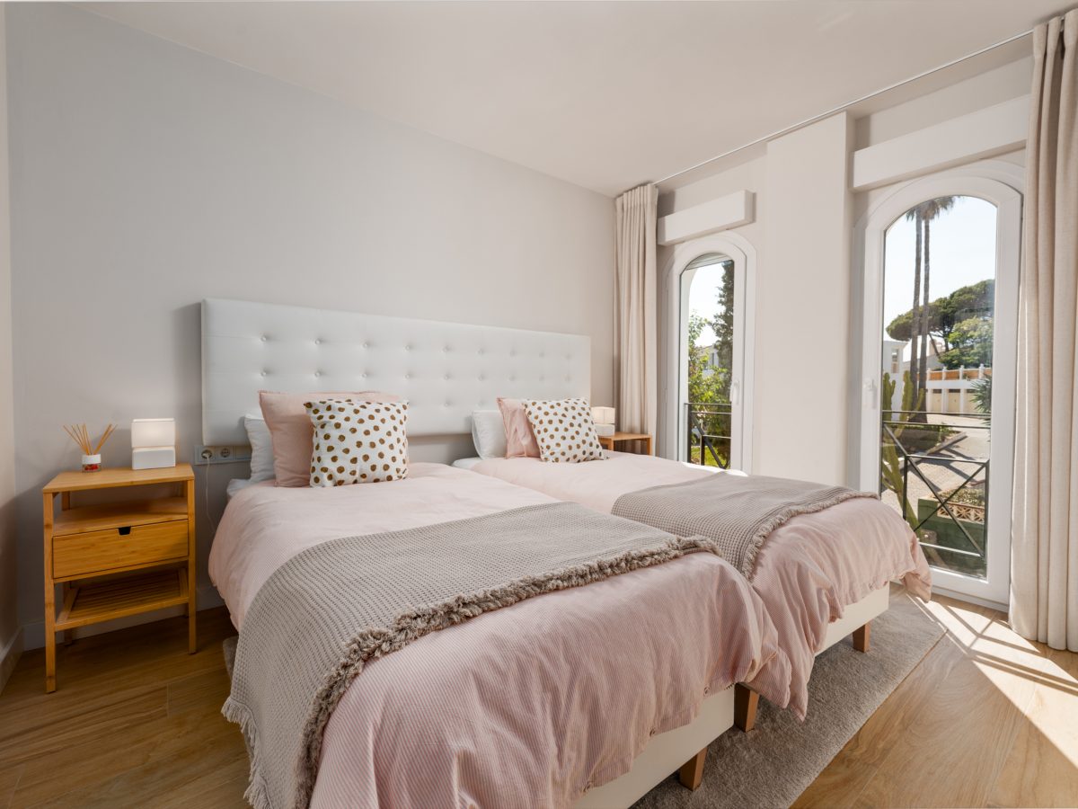 Bright twin bedroom with large windows and balcony at Playa del Moral apartment.