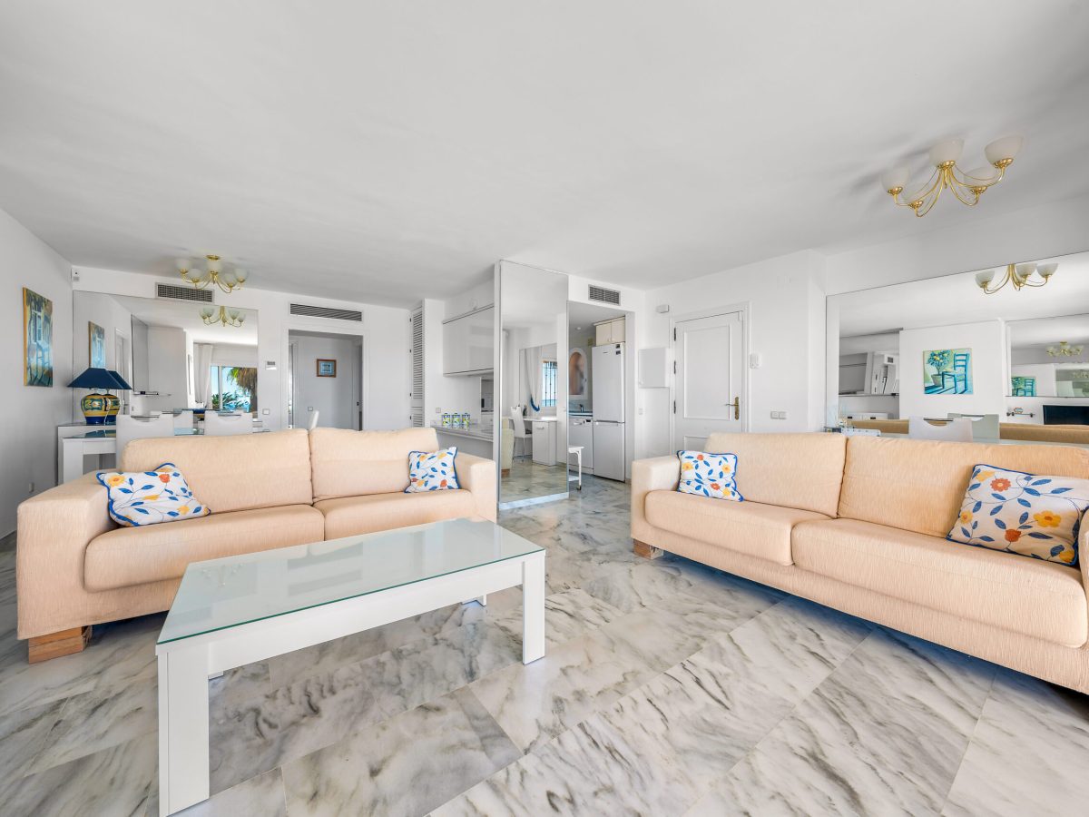 Open-plan living area with large windows facing the garden in Estepona apartment