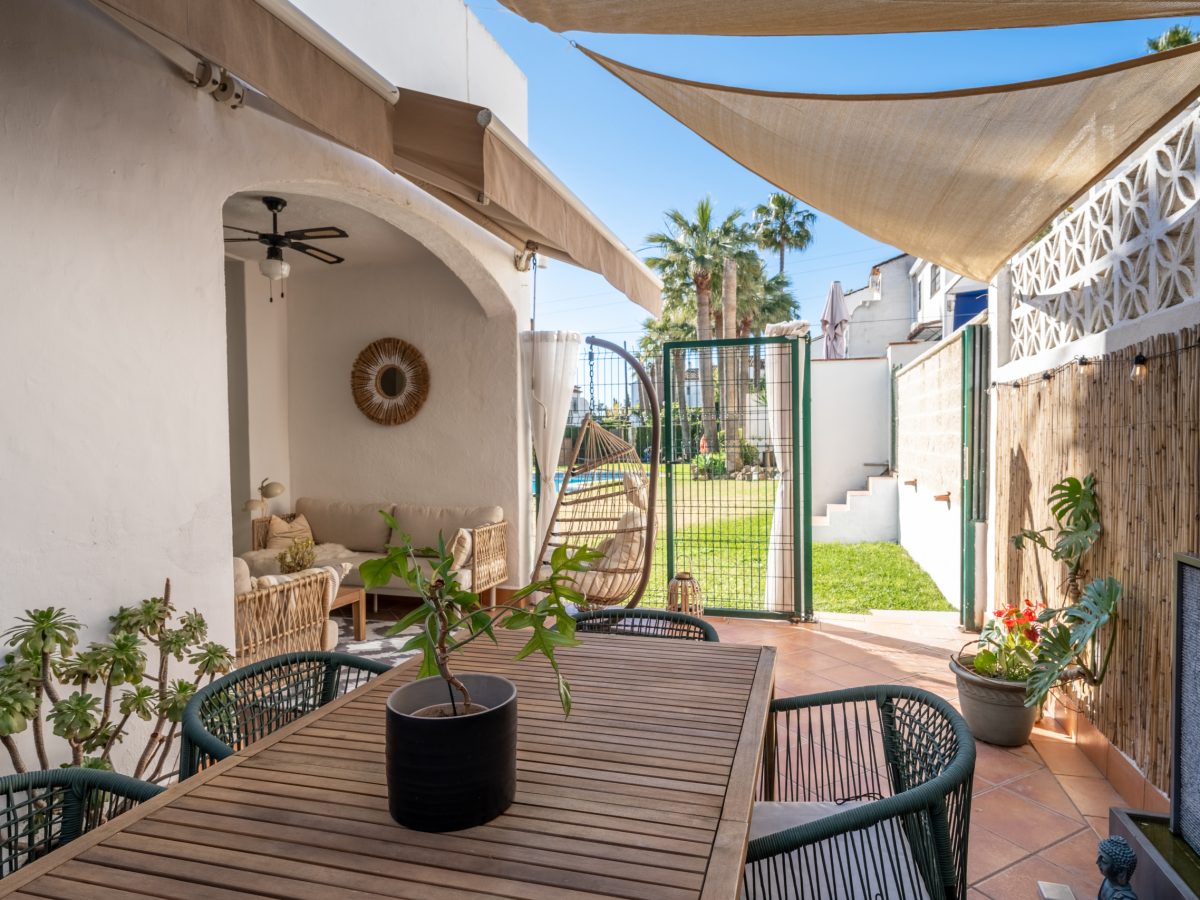 Outdoor patio and garden area of Bel-Air semi-detached house near Marbella, featuring dining table, sun shades, rattan furniture, and pool access