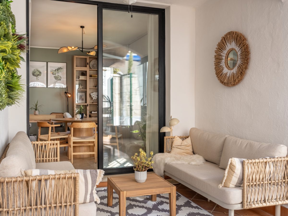 Cozy terrace lounge in Bel-Air semi-detached home near Marbella, with natural rattan furniture, indoor plants, and view into the modern dining area