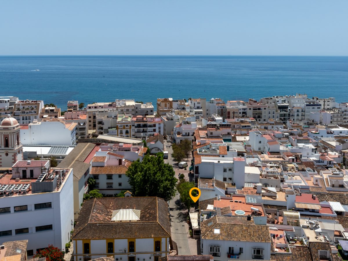 Aerial view of Estepona old town with Mediterranean Sea in the background, showing rooftops and coastal architecture.