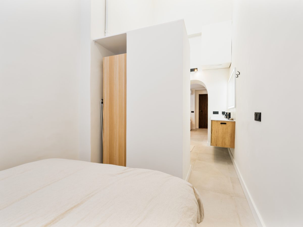 Bright minimalist bedroom with neutral decor and ensuite bathroom in Estepona old town apartment
