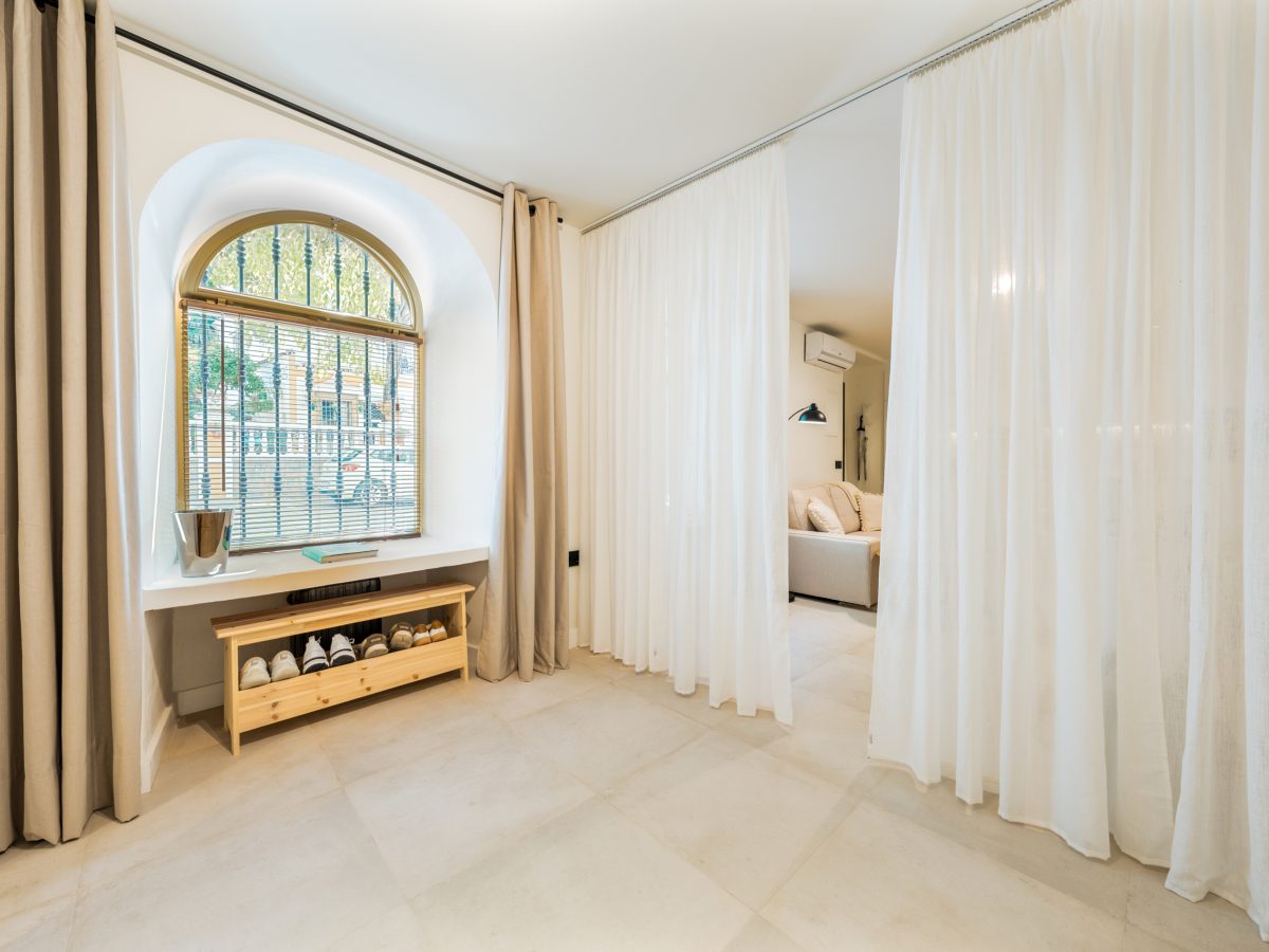 Bright interior with arched window, light curtains, and modern neutral decor in Estepona old town apartment