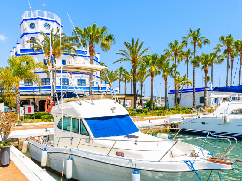 Luxury marina in Estepona, Costa del Sol — yachts docked at Puerto Deportivo surrounded by palm trees and white-blue Mediterranean architecture-Quintessentia Property Advisors