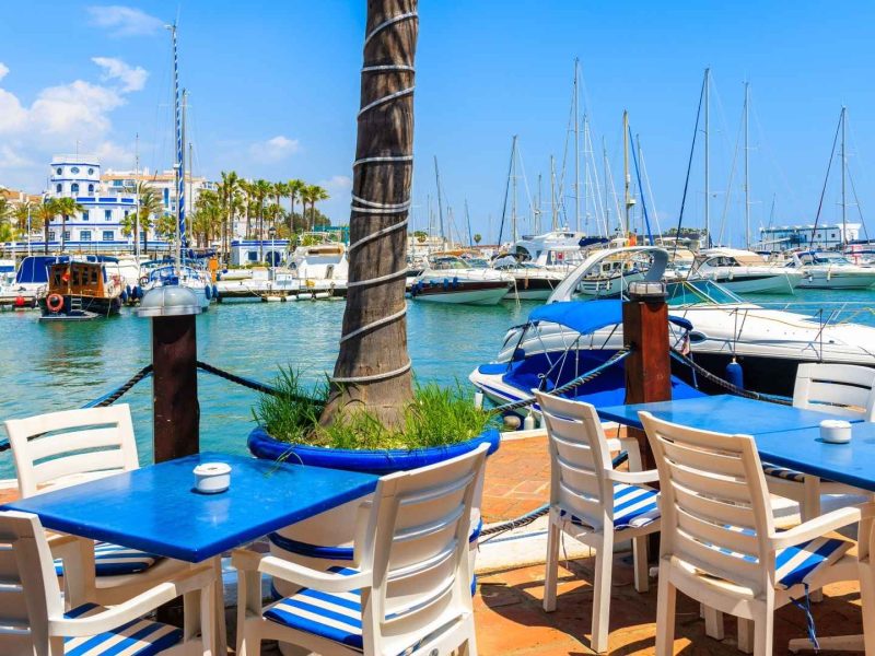 Colorful marina in Estepona with waterfront cafés, boats, and yachts — a popular family-friendly neighborhood on the Costa del Sol within the Estepona best areas.