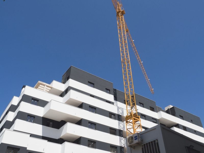 Modern apartment building under construction in Estepona, Costa del Sol, with crane against clear blue sky.