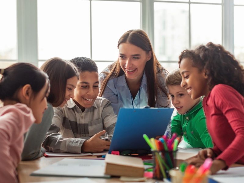 Teacher guiding international students during a collaborative classroom activity at a modern school in Marbella.